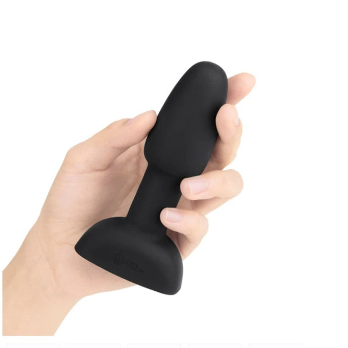 Black silicone rimming butt plug held in a hand with on a white background