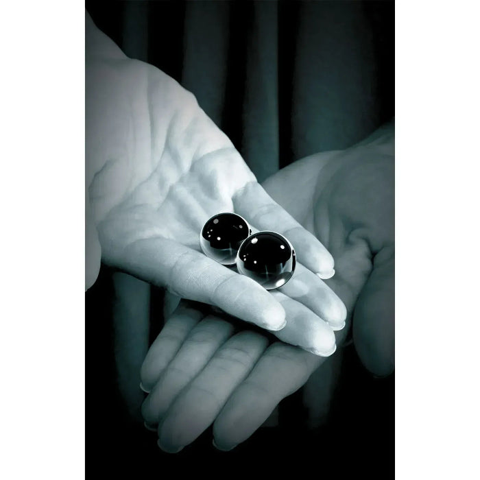 Black glass ben wa balls held in hand to show siz
