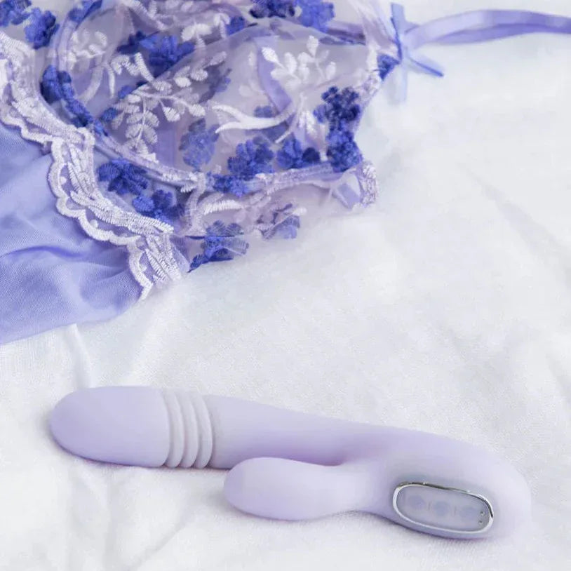 Playboy Bumping Bunny heated rabbit vibrator styled with black lace lingerie on white bedding