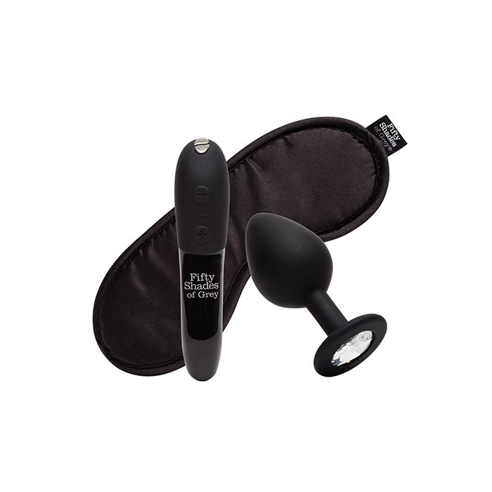 Fifty Shades of Grey & We-Vibe Come To Bed Kit with couples vibrator, bullet vibrator, and satin blindfold on a soft, neutral background