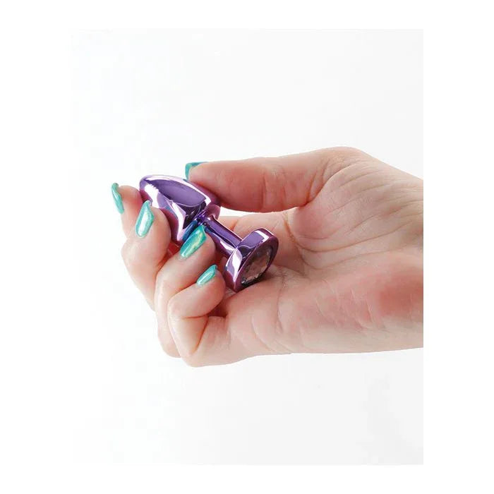 Woman holding Rear Assets Petite Anal Plug in hand, shiny purple jewel base lightweight aluminum safe flared design for beginner backdoor play.