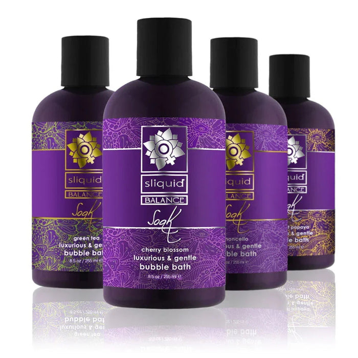 Four Sliquid Balance Soak bubble bath bottles in all scents - Cherry Blossom, Limoncello, Coconut Papaya, and Green Tea - standing together on a white background, showing the full scent range.