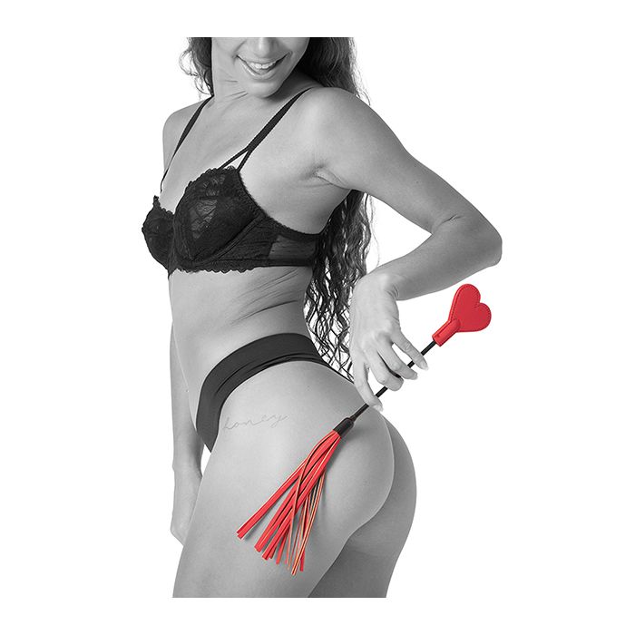 Woman in black lingerie holding a red and black versatile Amor Crop by Sportssheets on a white background