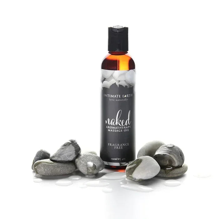 A bottle of Naked fragrance free aromatherapy massage oil with river rocks on white background