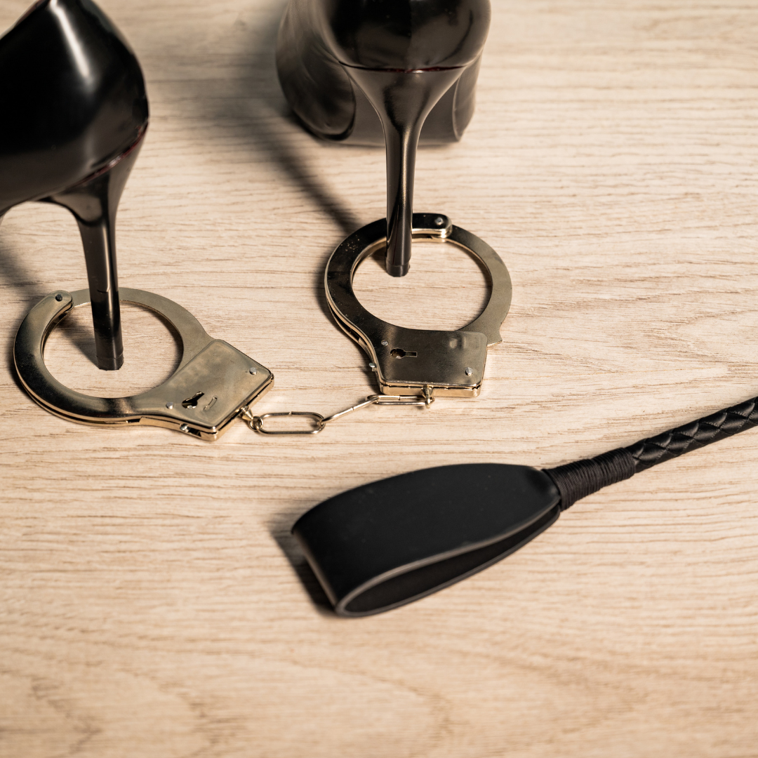 black stiletto heels with metal handcuffs and a crop