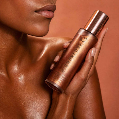 Model holding HighOnLove Shimmering Body Oil to glowing skin for a radiant illuminated finish
