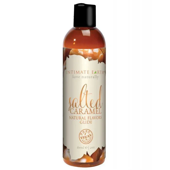 Intimate Earth Salted Caramel Oral Pleasure Glide bottle with gold-brown label featuring caramel swirl design; vegan, edible, pH balanced, water-based lubricant safe for sensitive skin and all erogenous zones, travel size 2 oz.