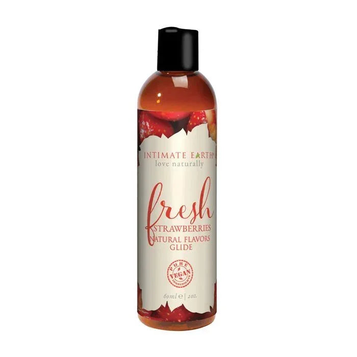 Intimate Earth Fresh Strawberries Natural Flavors Glide bottle with bright pink-red label featuring strawberry graphics; vegan, edible, pH balanced, water-based lubricant ideal for sensitive skin and all erogenous zones; convenient 2 oz travel size.