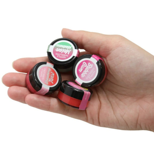 Hand holding an assortment of colorful flavored nipple nibblers, lip and nip balm variety pack for sensual care