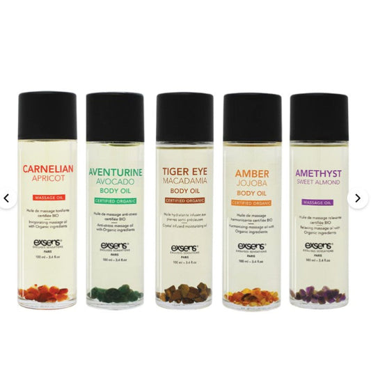 All five Crystal Body and Massage Oil by Exsens - bottles shown with real semi-precious crystals and vibrant botanical oils