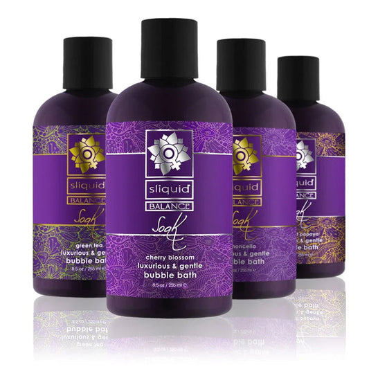 Four Sliquid Balance Soak bubble bath bottles in all scents - Cherry Blossom, Limoncello, Coconut Papaya, and Green Tea - standing together on a white background, showing the full scent range.