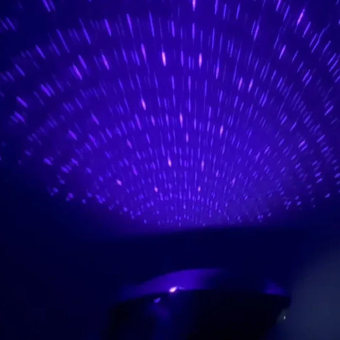 Soft purple starry light from the Pulse Galaxie mood projector casting galaxy-like patterns across a dark bedroom wall, creating a cozy, sensual atmosphere for intimate play. 
