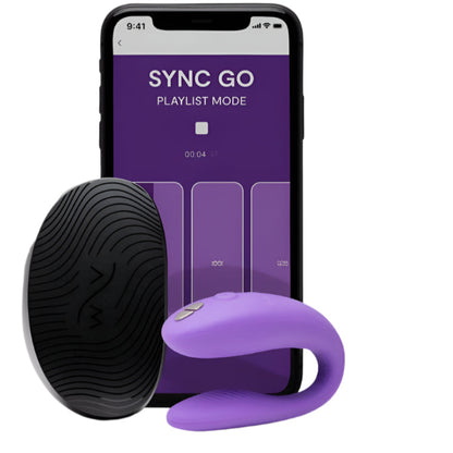 Purple We-Vibe Sync Go couples vibrator positioned beside its compact travel case, highlighting the smooth, body-safe silicone finish. An iPhone displaying the We-Vibe Sync Go app interface sits alongside the set, showcasing app-controlled features.